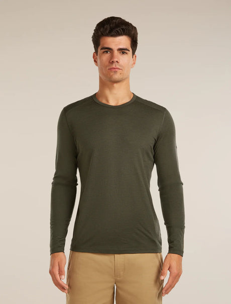 Man wearing a green long-sleeve shirt against a beige background - Icebreaker Merino 200 Oasis Long Sleeve Crew Thermal Top (Men's) - Dark Loden