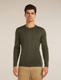 Man wearing a green long-sleeve shirt against a beige background - Icebreaker Merino 200 Oasis Long Sleeve Crew Thermal Top (Men's) - Dark Loden