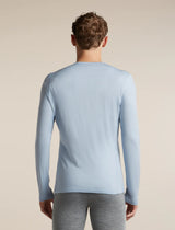 A man viewed from the back wearing a light blue long-sleeve crewneck shirt and gray heather pants, set against a plain beige studio background. - Icebreaker Merino 200 Oasis Long Sleeve Crew Thermal Top (Men's) - Zinc Blue