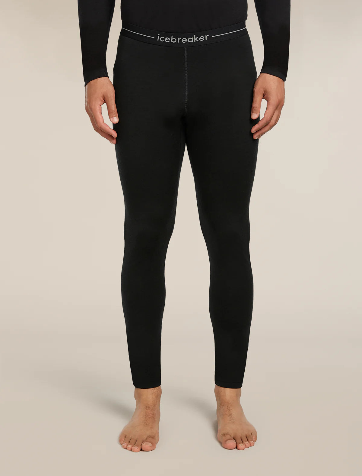 Person wearing black leggings with 'icebreaker' branding on a beige background - Icebreaker Merino 200 Oasis Thermal Leggings (Men's) - Black