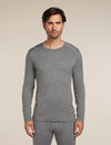A man wearing a heather gray long-sleeve crewneck shirt and matching gray pants, standing against a plain beige studio background. - Icebreaker Merino 260 Oasis Long Sleeve Crew Thermal Top (Men's) - Gritstone Heather