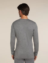 A man viewed from the back wearing a heather gray long-sleeve crewneck shirt and matching gray pants against a plain beige studio background. - Icebreaker Merino 260 Oasis Long Sleeve Crew Thermal Top (Men's) - Gritstone Heather
