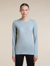 A woman modeling a light blue long-sleeve crewneck athletic top against a solid beige background. - Icebreaker Merino 200 Oasis Long Sleeve Crew Thermal Top (Women's) - Zinc Blue
