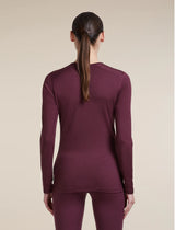 A woman viewed from the back wearing a fitted long-sleeve crew-neck top and matching leggings in a deep plum-burgundy color, against a plain warm beige studio background. - Icebreaker Merino 200 Oasis Long Sleeve Crew Thermal Top (Women's) - Dark Berry