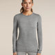 A woman modeling a fitted long-sleeve crewneck top in heather gray, paired with matching gray leggings, against a plain beige studio background. - Icebreaker Merino 260 Oasis Long Sleeve Crew Thermal Top (Women's) - Metro Heather