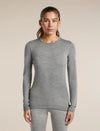 A woman modeling a fitted long-sleeve crewneck top in heather gray, paired with matching gray leggings, against a plain beige studio background. - Icebreaker Merino 260 Oasis Long Sleeve Crew Thermal Top (Women's) - Metro Heather