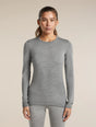 A woman modeling a fitted long-sleeve crewneck top in heather gray, paired with matching gray leggings, against a plain beige studio background. - Icebreaker Merino 260 Oasis Long Sleeve Crew Thermal Top (Women's) - Metro Heather