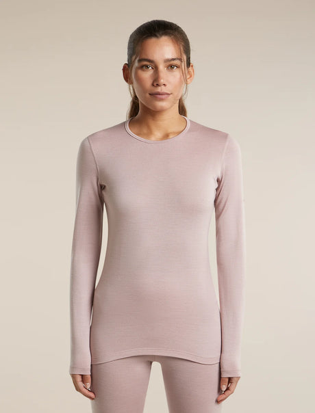 A woman modeling a long-sleeve crewneck top in a dusty mauve-pink color, paired with matching leggings, against a solid light beige background. - Icebreaker Merino 260 Oasis Long Sleeve Crew Thermal Top (Women's) - Pink Quartz