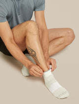 Person wearing light gray socks on a beige background - Icebreaker Merino Multisport Light Mini Socks (Men's) - Ecru Heather/Alloy/Snow