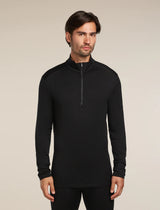 Man wearing a black long-sleeve shirt with a quarter zip on a beige background - Icebreaker Merino 260 Tech Long Sleeve Half Zip (Men's) - Black
