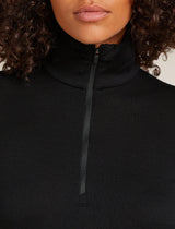 Close-up of a person wearing a black turtleneck sweater with a zipper. - Icebreaker Merino 260 Tech Long Sleeve Half Zip Thermal Top (Women's) - Black