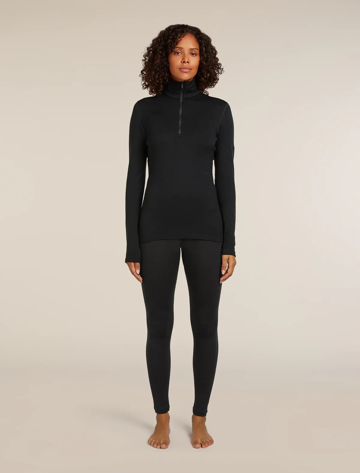 Woman wearing a black long-sleeve top and leggings on a beige background - Icebreaker Merino 260 Tech Long Sleeve Half Zip Thermal Top (Women's) - Black