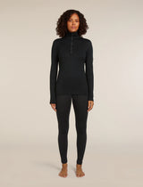 Woman wearing a black long-sleeve top and leggings on a beige background - Icebreaker Merino 260 Tech Long Sleeve Half Zip Thermal Top (Women's) - Black