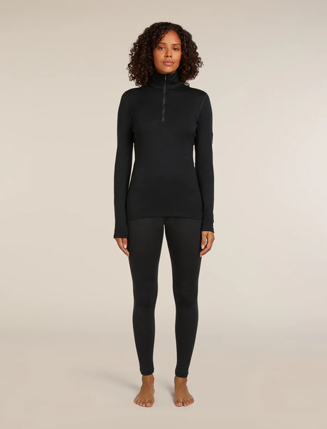 Woman wearing a black long-sleeve top and leggings on a beige background - Icebreaker Merino 260 Tech Long Sleeve Half Zip Thermal Top (Women's) - Black