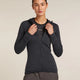 Person wearing a dark gray hoodie with a visible brand logo on a beige background - Icebreaker Merino Blend 200 Realfleece Descender Long Sleeve Zip Hoodie (Women's) - Jet Heather/Black