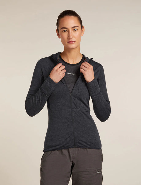 Person wearing a dark gray hoodie with a visible brand logo on a beige background - Icebreaker Merino Blend 200 Realfleece Descender Long Sleeve Zip Hoodie (Women's) - Jet Heather/Black