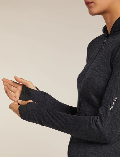 Person wearing a dark gray long-sleeve shirt with a visible brand logo on a beige background - Icebreaker Merino Blend 200 Realfleece Descender Long Sleeve Zip Hoodie (Women's) - Jet Heather/Black