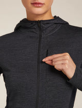 Person wearing a dark gray hoodie with a zipper, pointing to the zipper. - Icebreaker Merino Blend 200 Realfleece Descender Long Sleeve Zip Hoodie (Women's) - Jet Heather/Black