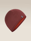 A dark red knit beanie hat with a small gray brand tag on the side, displayed against a light beige gradient background. - Icebreaker Merino 200 Pocket Hat (Unisex) - Agate/Port
