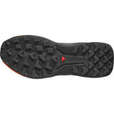 The outsole of a Salomon trail running shoe, showing deep lugs and the Salomon logo with a red triangle on a black rubber tread. - Salomon Genesis 2 Shoes (Women's) - Huckleberry/Black/Red Orange