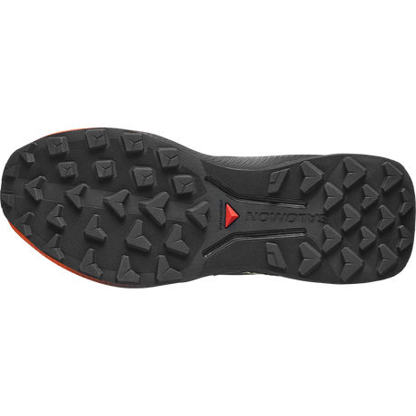 The outsole of a Salomon trail running shoe, showing deep lugs and the Salomon logo with a red triangle on a black rubber tread. - Salomon Genesis 2 Shoes (Women's) - Huckleberry/Black/Red Orange