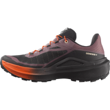 A single trail running shoe shown in a side profile view against a solid white background. The shoe features a dark gray and black mesh upper with a dusty purple collar, bright orange laces, and a thick black midsole with a vibrant orange outsole. - Salomon Genesis 2 Shoes (Women's) - Huckleberry/Black/Red Orange