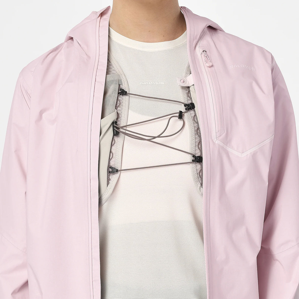 Person wearing a light pink jacket over a white shirt with a graphic design. - Salomon Bonatti Pro Jacket (Women's) - Icy Pink