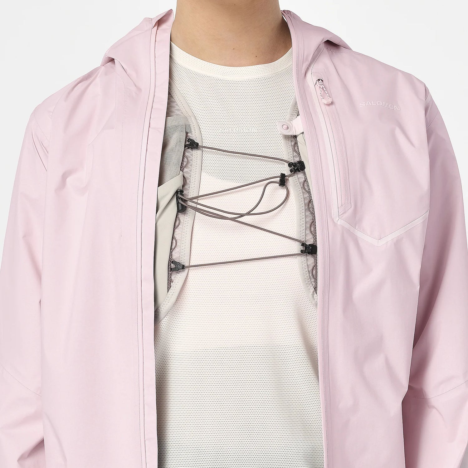 Person wearing a light pink jacket over a white shirt with a graphic design. - Salomon Bonatti Pro Jacket (Women's) - Icy Pink