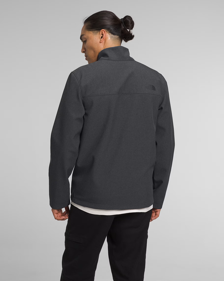 A man viewed from the back wearing a dark gray zip-up fleece jacket with a stand collar, black pants, and a white undershirt, against a light gray studio background. The small black embroidered logo of The North Face is visible on the upper right shoulder. - The North Face Apex Bionic 3 Jacket (Men's) - TNF Dark Grey Heather