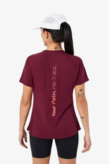 Person wearing a maroon t-shirt with text on the back, standing against a white background - NNormal Race T-Shirt 02 (Women's) - Burgundy
