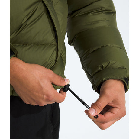 Close-up of a person wearing an olive green puffer jacket, demonstrating how to adjust the black drawstring on the cuff. - The North Face 1996 Retro Nuptse Jacket (Men's) - Woodland Green/TNF Black