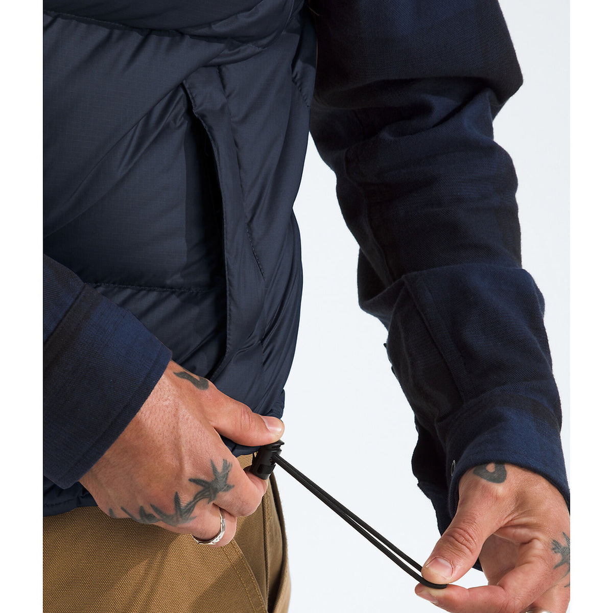 Person adjusting a cord on a jacket with a neutral background - The North Face 1996 Retro Nuptse Vest (Men's) - Summit Navy/TNF Black-Recycled Down