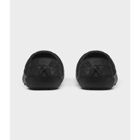 A pair of black slip-on clogs shown from the back, featuring a quilted pattern on the upper and a thick black sole, set against a light gray background. - The North Face ThermoBall Traction V Mules (Men's) - TNF Black/TNF White