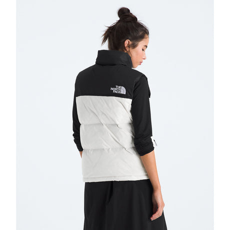 Person wearing a black and white jacket with The North Face logo on a white background - The North Face 1996 Retro Nuptse Vest (Womens) - White Dune/TNF Black-Recycled Down