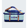 A light blue and navy duffel bag with bright orange straps and accents, featuring multiple brand patches on the front, set against a light gray background. - The North Face Base Camp Duffel Small 50L - Canal Blue/Bold Blue/Papaya