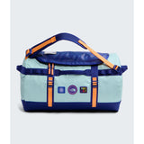 A light blue and navy duffel bag with bright orange straps and accents, featuring multiple brand patches on the front, set against a light gray background. - The North Face Base Camp Duffel Small 50L - Canal Blue/Bold Blue/Papaya