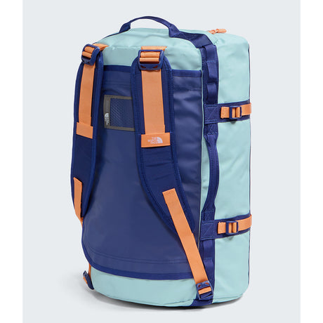 A light blue and navy blue duffel bag with orange straps and buckles, shown from the back on a light gray background. The brand 'The North Face' is visible on a small orange tag on the front strap. - The North Face Base Camp Duffel Small 50L - Canal Blue/Bold Blue/Papaya