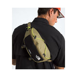 Person wearing a green and black sling bag with 'The North Face' logo on a white background - The North Face Terra Lumbar 6L - Cedar/TNF Black/Fizz Lime