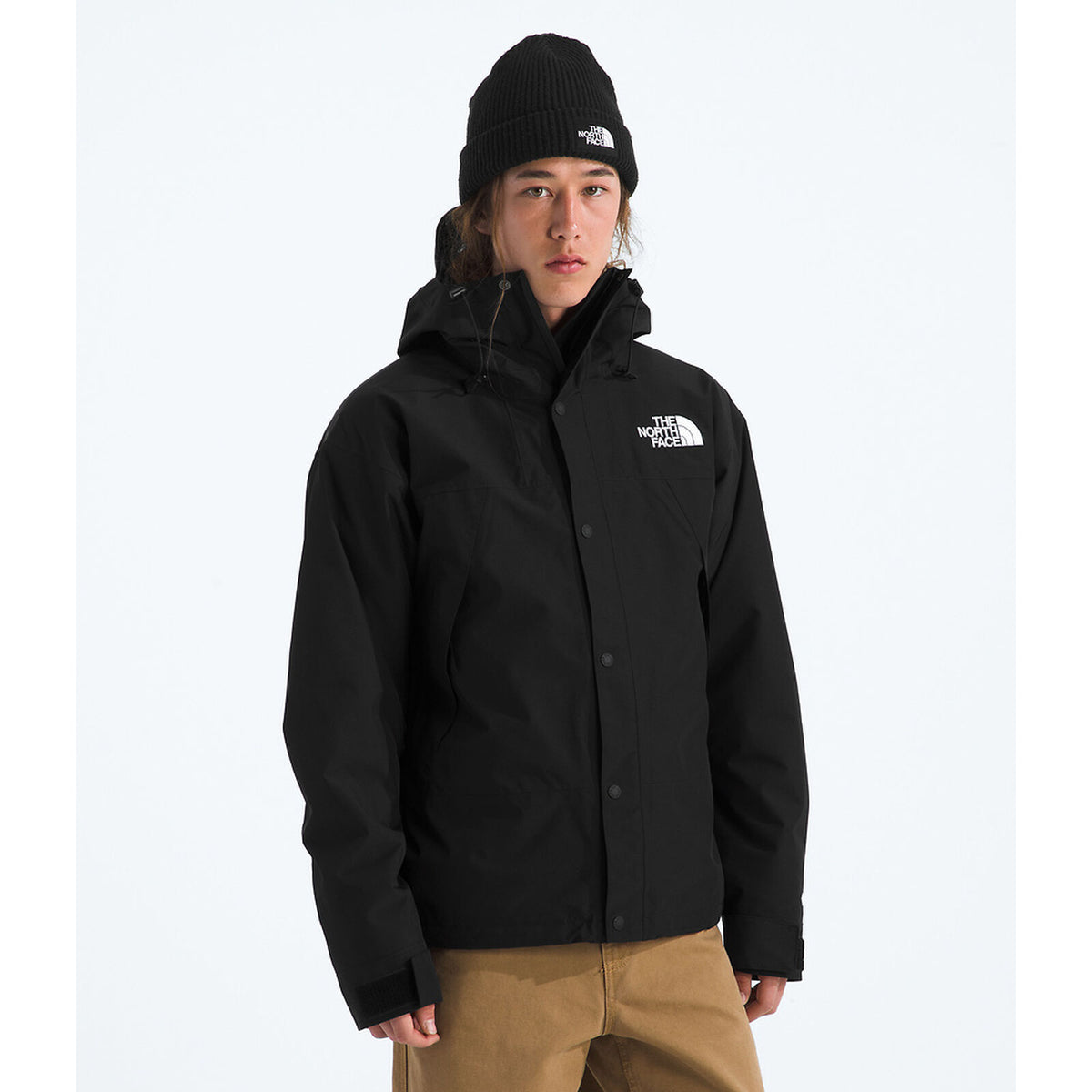 Person wearing a black jacket with a brand logo on a white background - The North Face GORE-TEX Mountain Jacket (Men's) - TNF Black/TNF Black/TNF Black