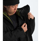 Person wearing a black jacket with a hood, adjusting it on a white background - The North Face GORE-TEX Mountain Jacket (Men's) - TNF Black/TNF Black/TNF Black