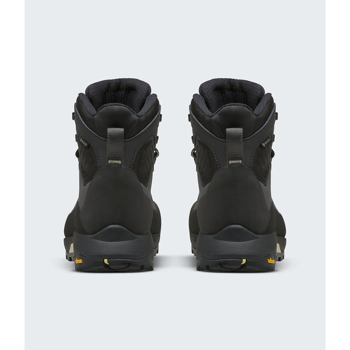 A pair of black high-top hiking boots shown from the back, featuring a matte finish with small gold accents on the pull tabs and outsole. - The North Face Verto Alpine Mid GORE-TEX Boots (Women's) - Anthracite Grey/Lemon Mist