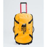 The North Face yellow rolling duffel bag with black straps, a black logo, and a red telescoping handle on a light gray background. - The North Face Base Camp Rolling Thunder 28" (95L) - Summit Gold/TNF Gold-NPF