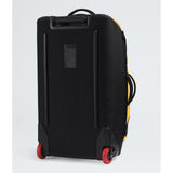 A black soft-sided rolling suitcase with red wheels, shown from a rear three-quarter angle against a light gray studio background. - The North Face Base Camp Rolling Thunder 28" (95L) - Summit Gold/TNF Gold-NPF