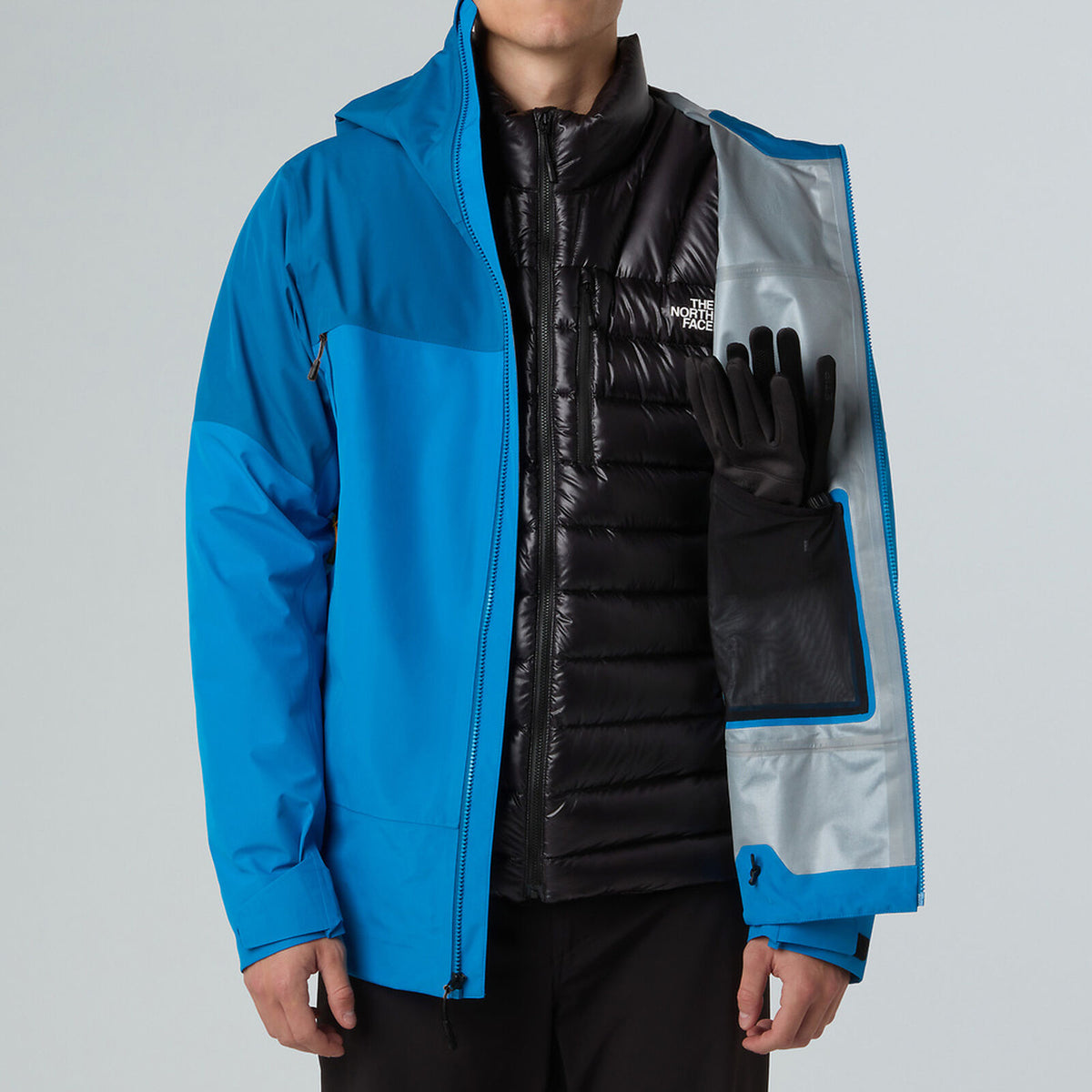 Person wearing a blue jacket with a black vest and gloves on a gray background - The North Face Jazzi 3L GORE-TEX Jacket (Men's) - Skyline Blue/Adriatic Blue