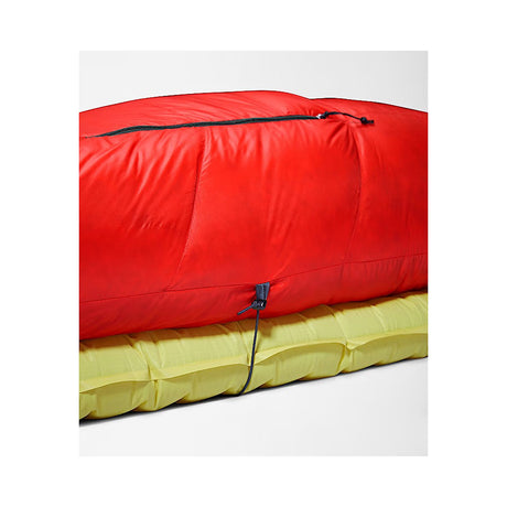A bright red sleeping bag or padded sleeping pad shown folded and stacked on top of a yellow padded item, photographed on a clean light gray studio background. - The North Face Inferno Sleeping Bag - 20F / -29C