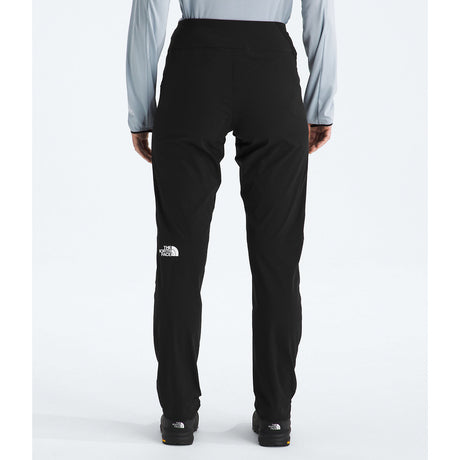 Rear view of a person wearing black The North Face pants with a light blue long-sleeve shirt, standing against a light gray studio background. - The North Face Summit Summit Series Off Width Pants (Women's) - TNF Black