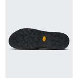 A close-up view of a black hiking shoe sole with a textured tread pattern and a small yellow Vibram logo in the center, set against a light gray background. - The North Face Verto Approach Shoes (Unisex) - Smoked Pearl/TNF Black
