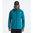 A man wearing a teal blue hooded jacket by The North Face, paired with a black beanie and black pants, standing against a light gray studio background. - The North Face Summit Series Off Width Jacket (Men's) - Dusk Blue