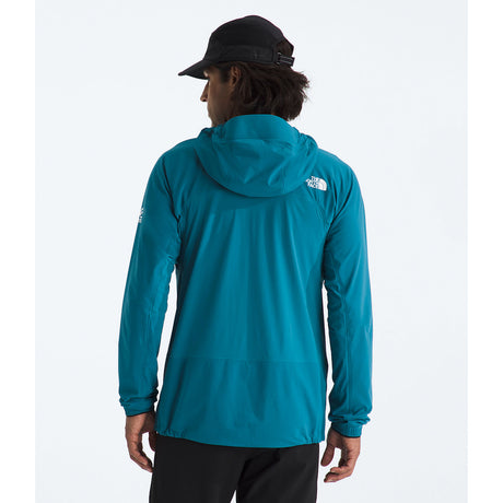 A person shown from the back wearing a teal hooded jacket with a small white The North Face logo on the left shoulder, a black cap, and black pants, against a clean white studio background. - The North Face Summit Series Off Width Jacket (Men's) - Dusk Blue