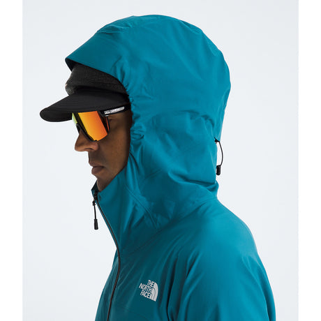 A side profile of a person wearing a teal hooded jacket by The North Face, a black cap, and mirrored sunglasses against a light gray studio background. - The North Face Summit Series Off Width Jacket (Men's) - Dusk Blue